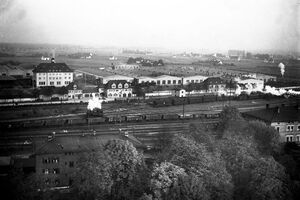 Das Foto zeigt Gebäude des Eisenbahnausbesserungswerkes am Hauptbahnhof Ingolstadt um 1927. Davor sind Gleise und Züge zu sehen.